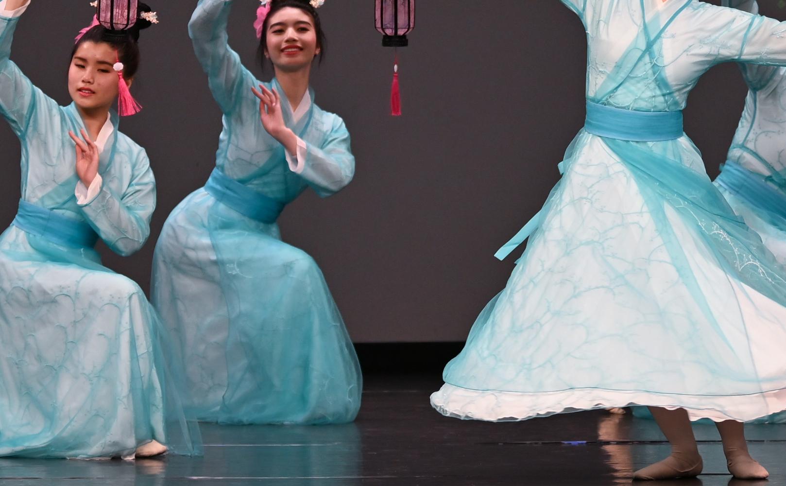 Group of femal dancers wearing light blue dresses.