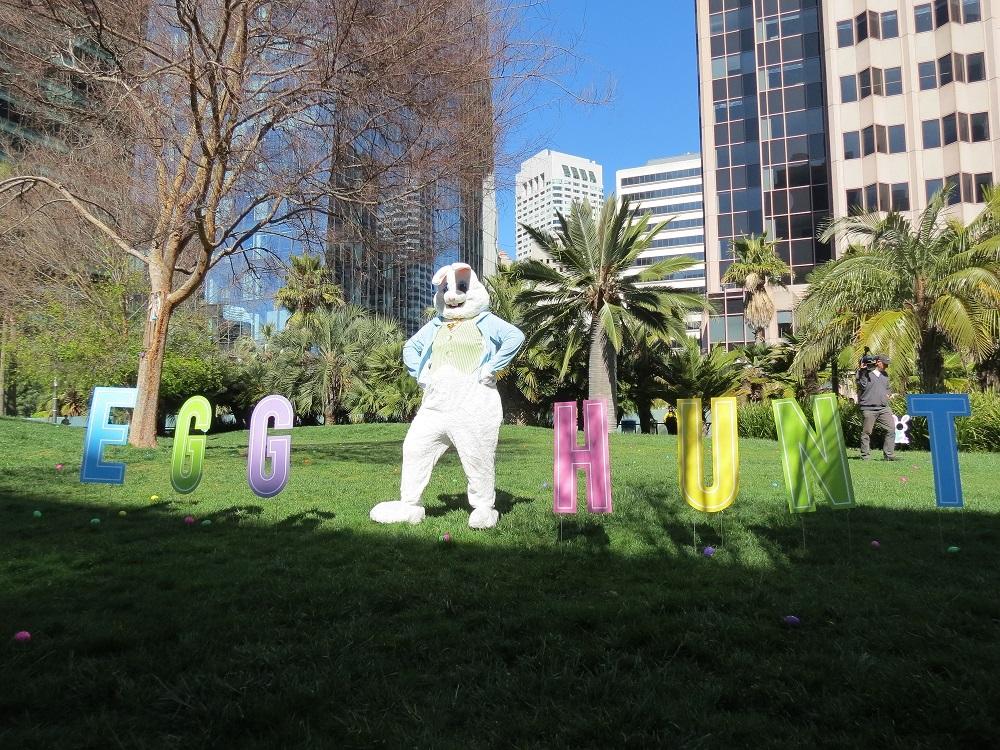 Egghunt sign with funny bunny standing in park.