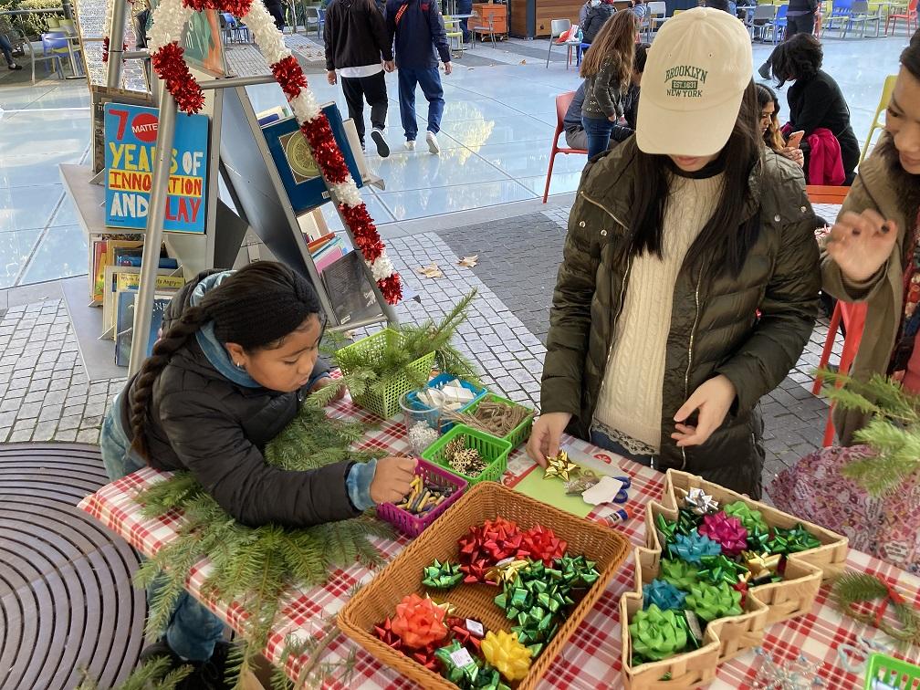 Young girl chooses decorations for a wreath. A table with different colored ribbons.