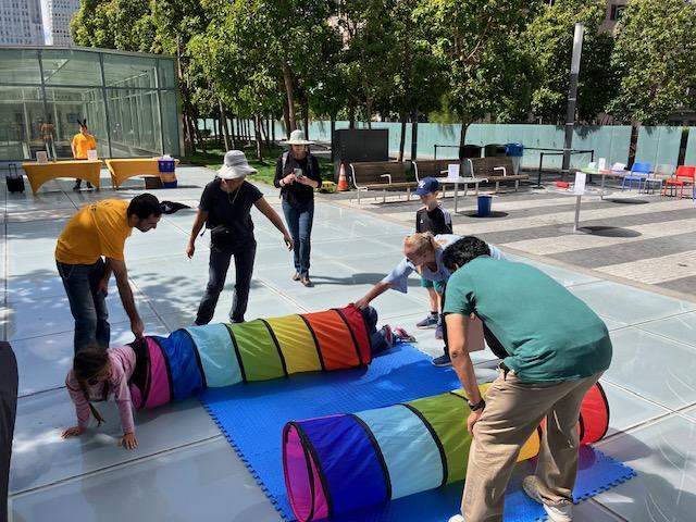 Colorful tubes activity, adults helping children.