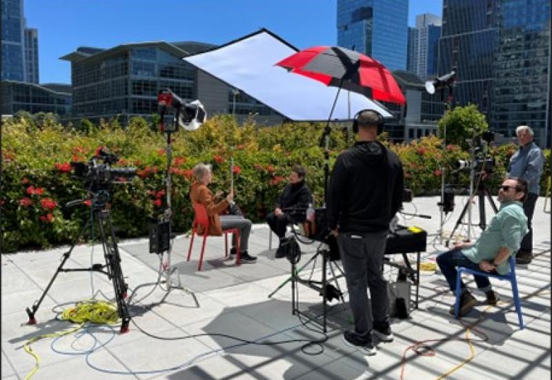 A group of people sitting outside with camera equipment.
