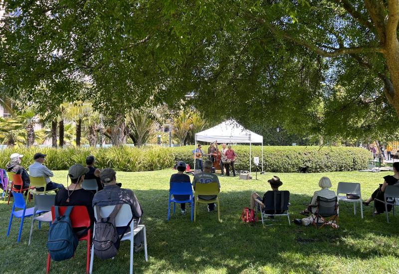 Audience watches band under tent on central lawn.