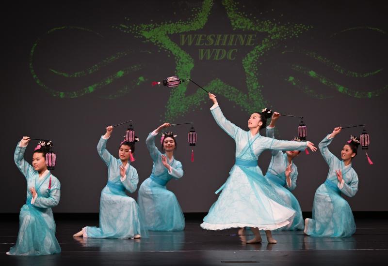 Group of femal dancers wearing light blue dresses.