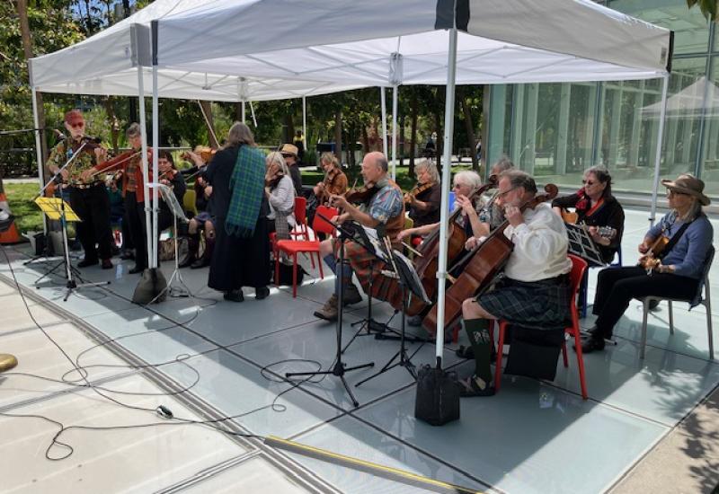 A band playing under an awning in a park.